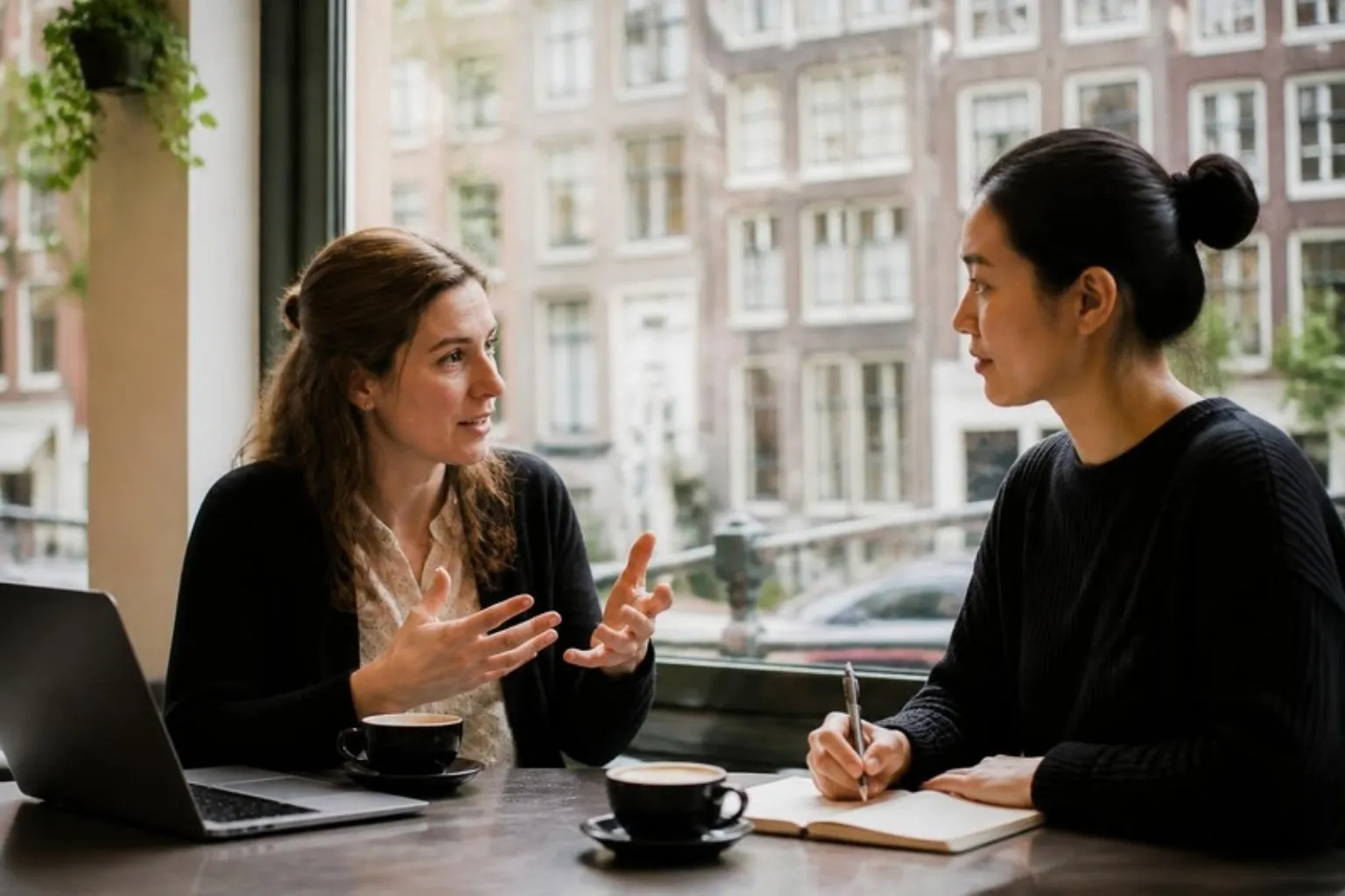 Two people in a one-to-one working conversation by a window in Amsterdam